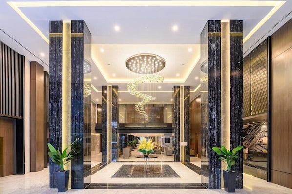 A modern lobby with marble columns, a central chandelier, and a reception area. - Aston Sorong Hotel and Conference Center (Sorong)