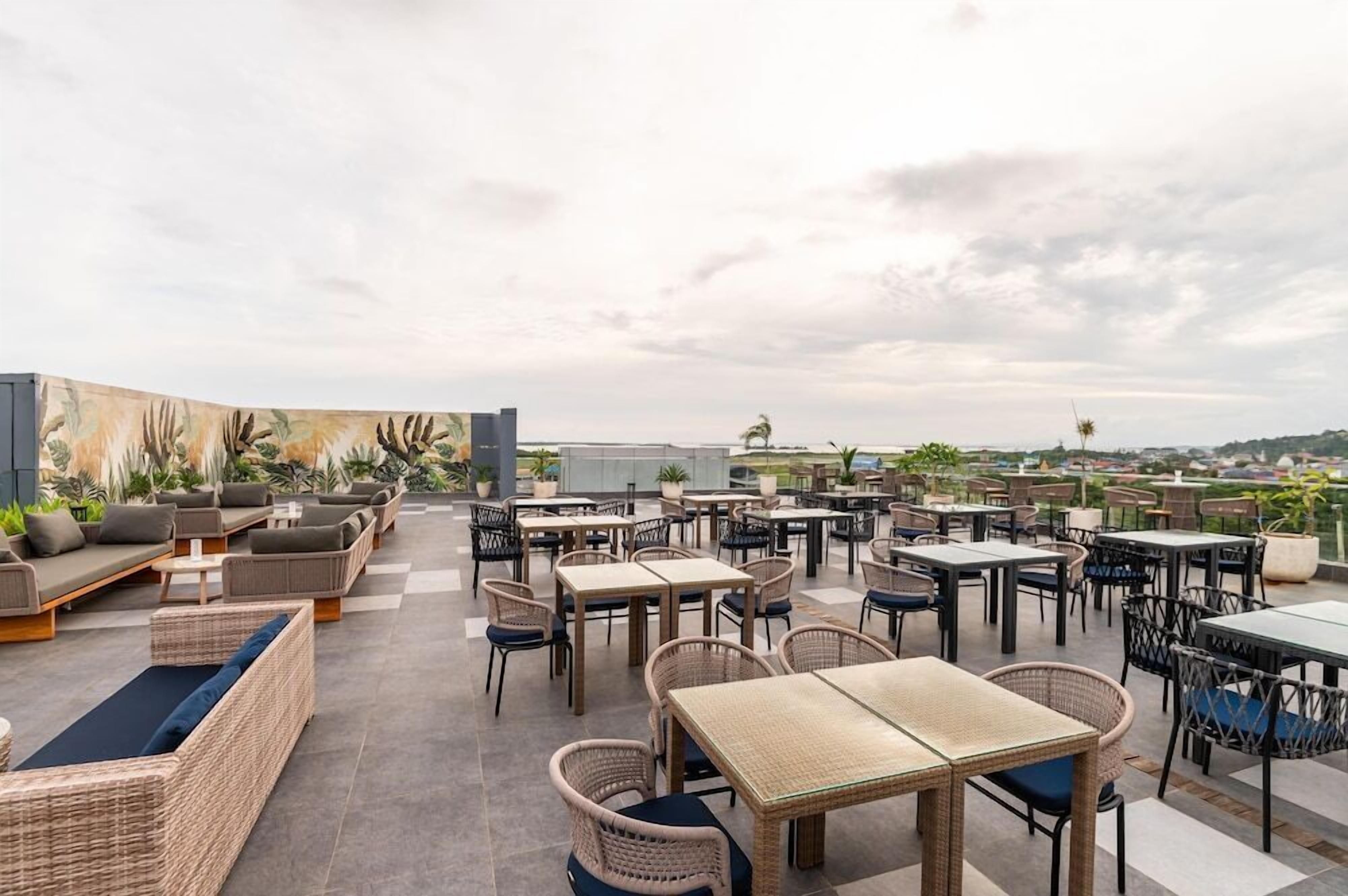 A rooftop terrace with outdoor seating and tables, offering a view of the cityscape.