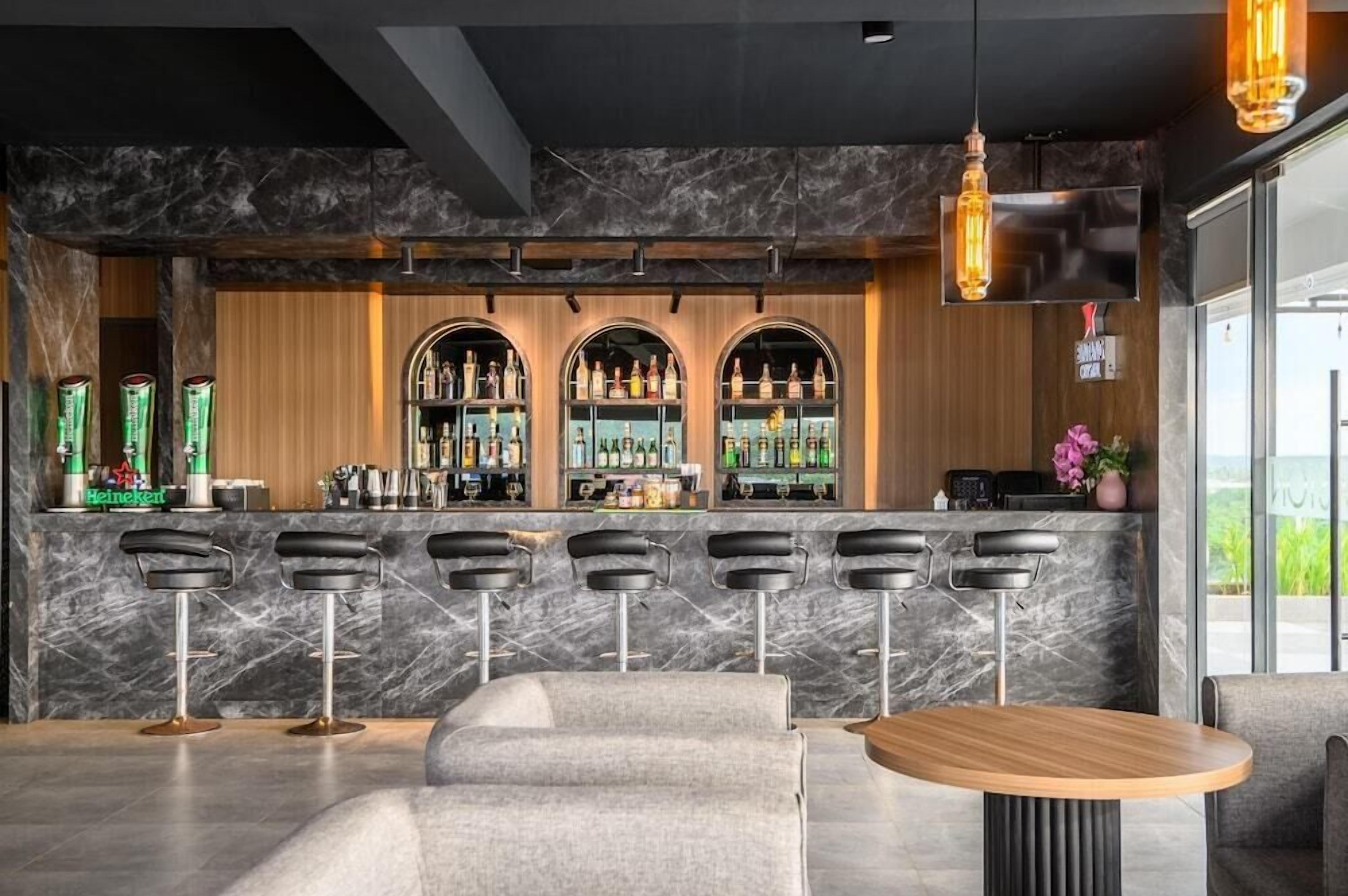 A bar area with a marble countertop, multiple stools, and a wooden bar counter.