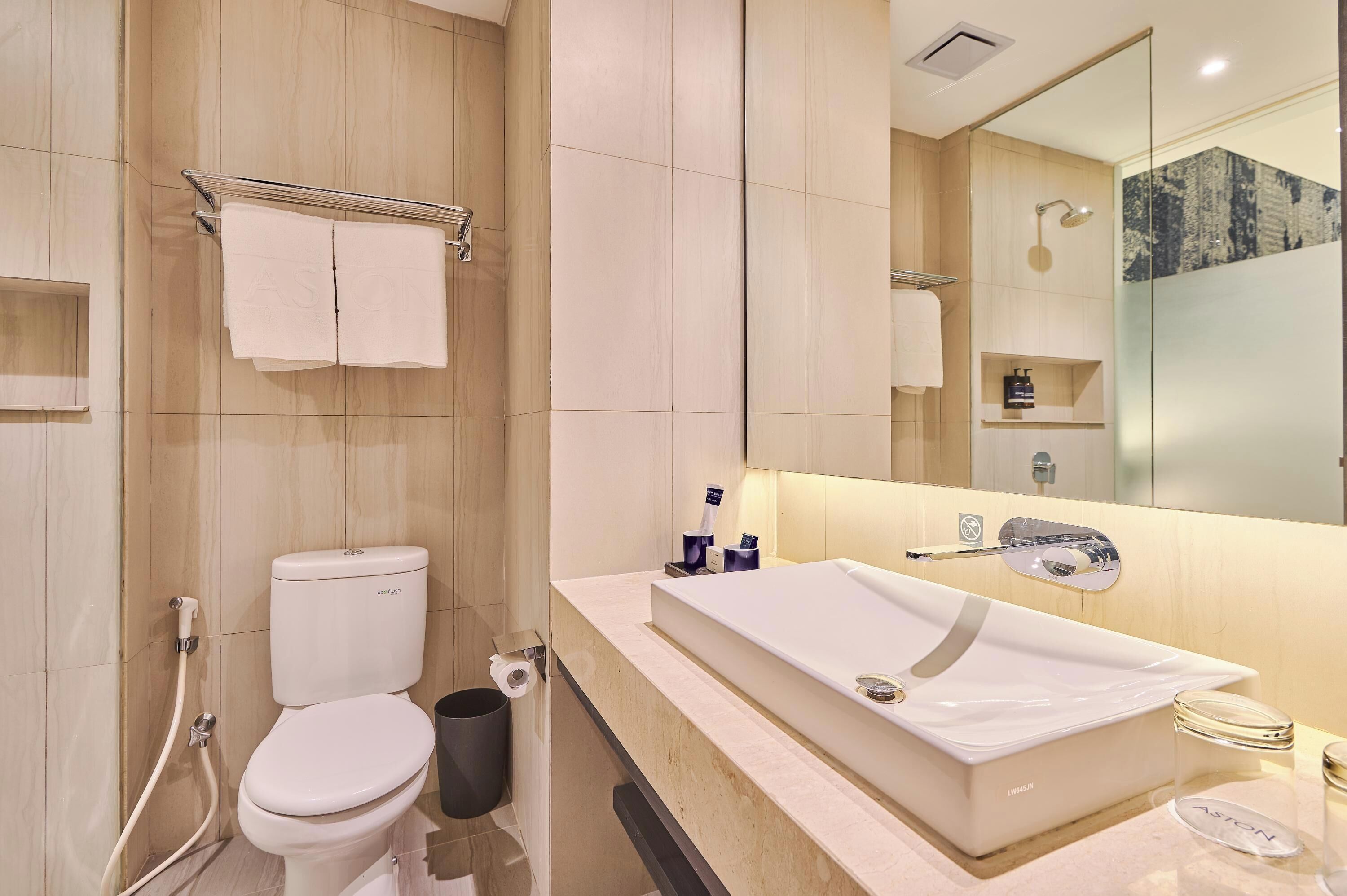 A modern bathroom with a toilet, bidet, and a large sink with a mirror above it.