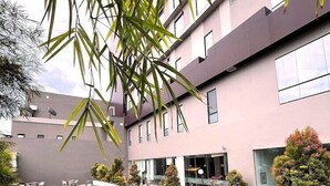 Un bâtiment moderne doté d’une piscine, entouré de verdure et surplombé d’un ciel dégagé.