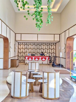 A modern hotel lobby with a reception desk, seating area, and a decorative wall. - The Allure Villas Managed by Sahid (Pangandaran)