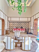 Un moderno vestíbulo de hotel con recepción, zona de estar y una pared decorativa.