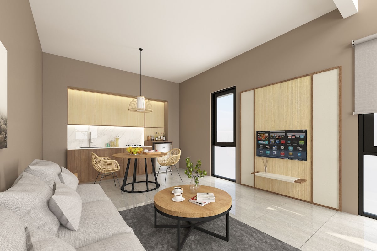 Uma sala de estar moderna com um sofá, uma mesa de centro e uma área de jantar com cadeiras, e uma cozinha ao fundo.