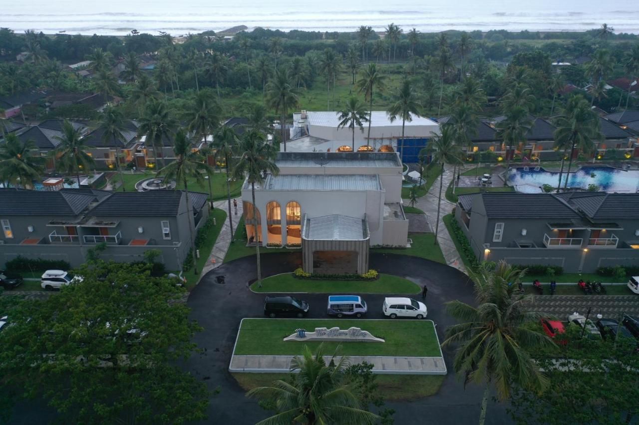 A resort with multiple buildings, a swimming pool, and palm trees.