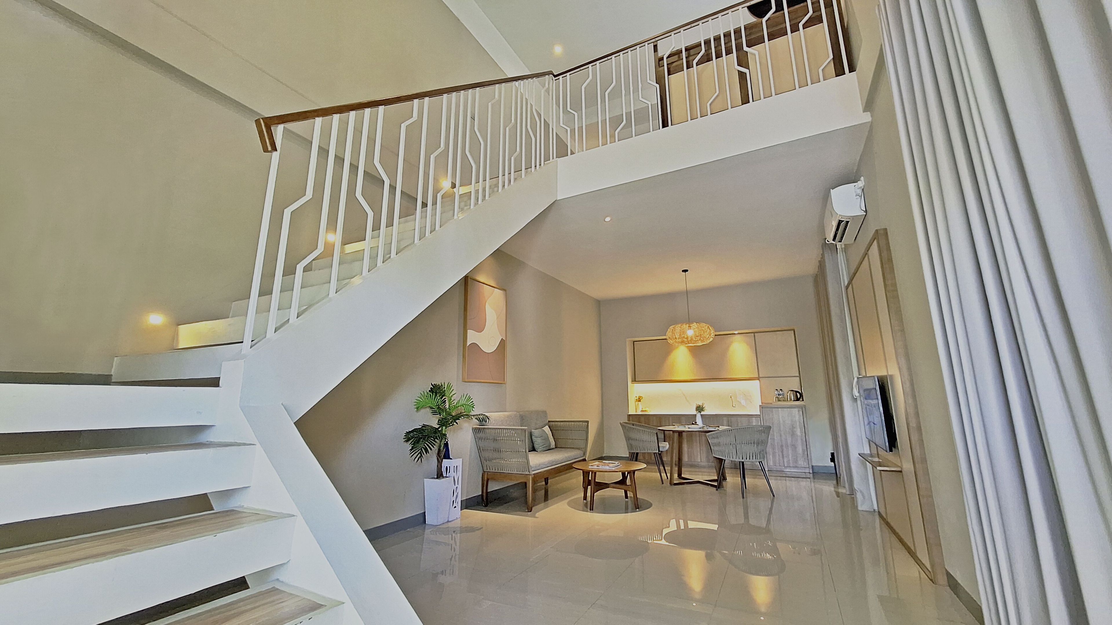 A spacious living area with a staircase, a dining table, and a sofa.