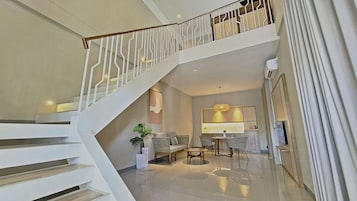 A spacious living area with a staircase, a dining table, and a sofa.