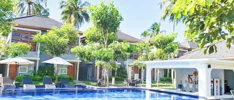 A swimming pool with lounge chairs, palm trees, and a building labeled 'K Pool & Spa'.