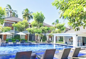 Una piscina con sillones de descanso, palmeras y un edificio que dice 'K Pool & Spa'.