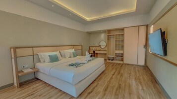 Una habitación de hotel moderna con una cama grande, mesitas de noche, un escritorio, un armario y un televisor montado en la pared.