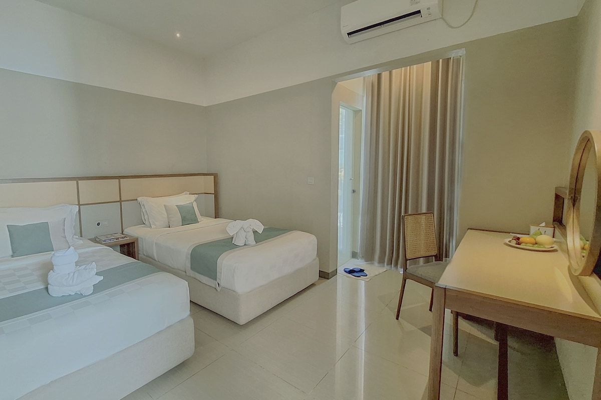 A hotel room with two beds, a desk, a chair, and a large mirror.
