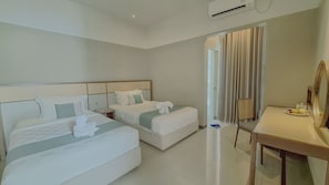 A hotel room with two beds, a desk, a chair, and a large mirror.