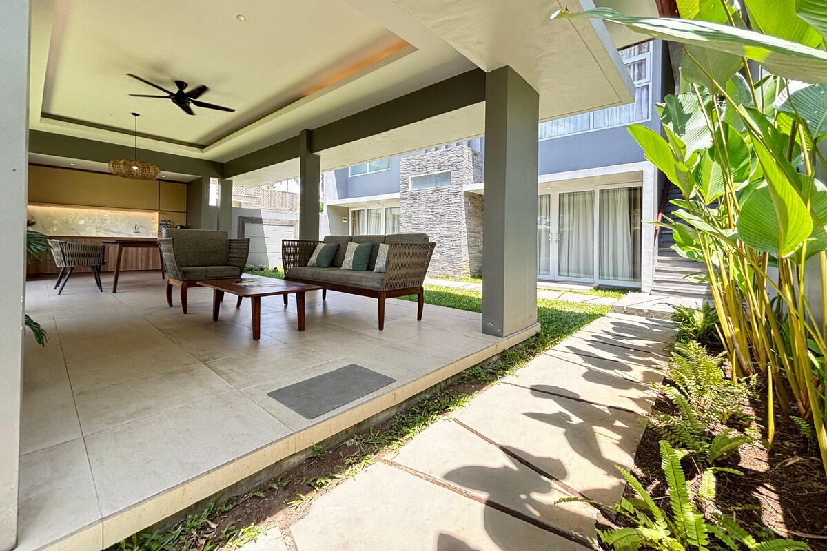 An outdoor patio area with a sofa, chairs, a coffee table, and a ceiling fan.