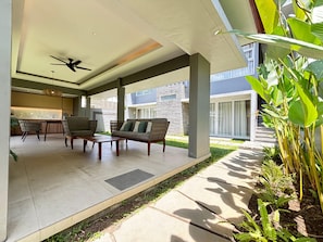 An outdoor patio area with a sofa, chairs, a coffee table, and a ceiling fan.