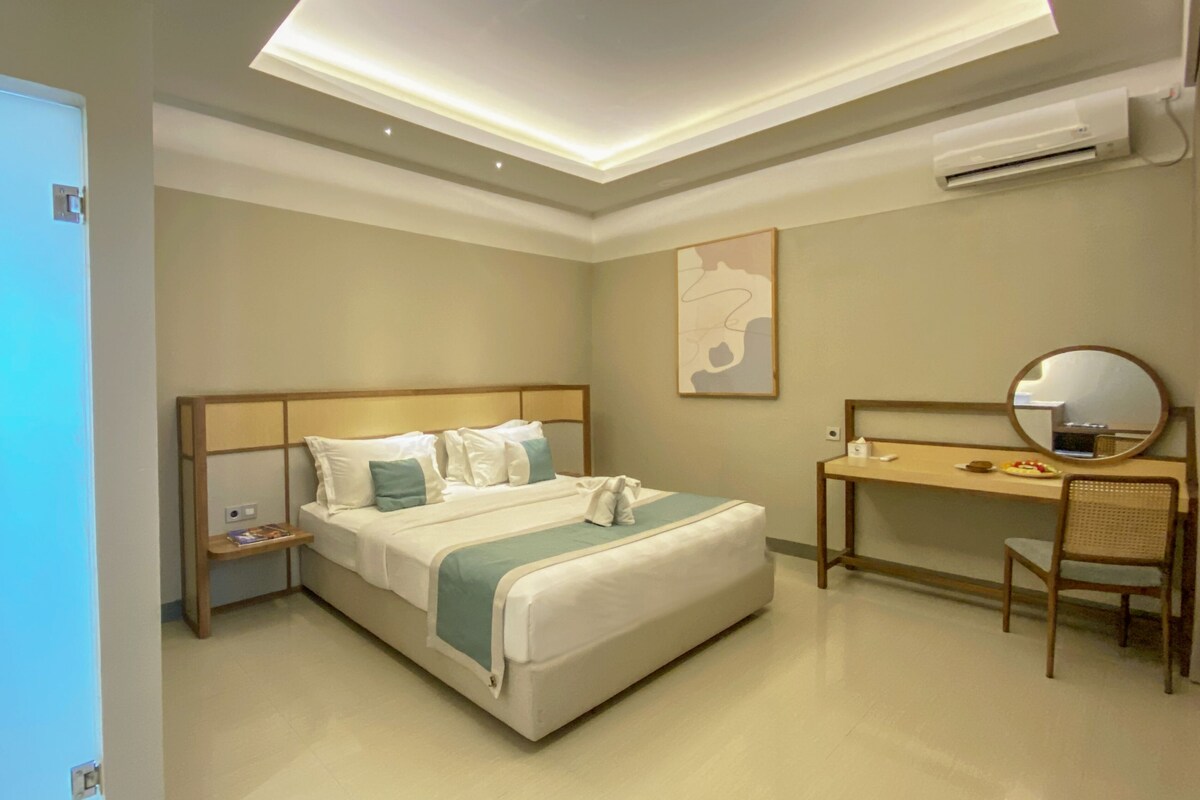 Une chambre d’hôtel équipée d’un lit, d’un bureau, d’une chaise, d’un miroir et d’un climatiseur fixé au mur.