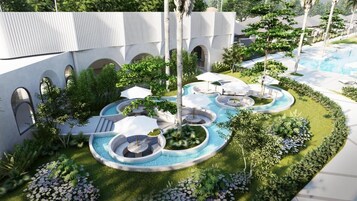 Zona de piscina con múltiples fuentes de agua, rodeada de vegetación y arcos arquitectónicos.