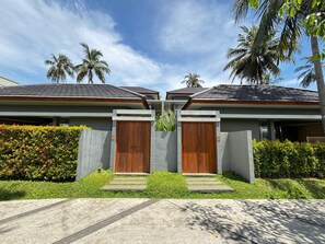 A modern two-story house with a concrete facade, wooden doors, and a well-maintained garden. - The Allure Villas Managed by Sahid (Pangandaran)