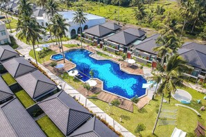 A resort with a large swimming pool, multiple villas, and palm trees. - The Allure Villas Managed by Sahid (Pangandaran)