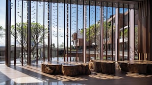 A modern interior with large windows, wooden seating, and a reflective floor.