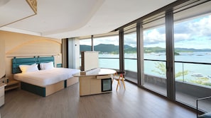 Ein modernes Hotelzimmer mit einem großen Bett, einem Schreibtisch und Meerblick.
