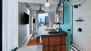 A modern hotel bathroom with a sink, mirror, and shower.