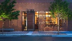 A modern building with a brick facade, a glass entrance, and a small outdoor seating area.