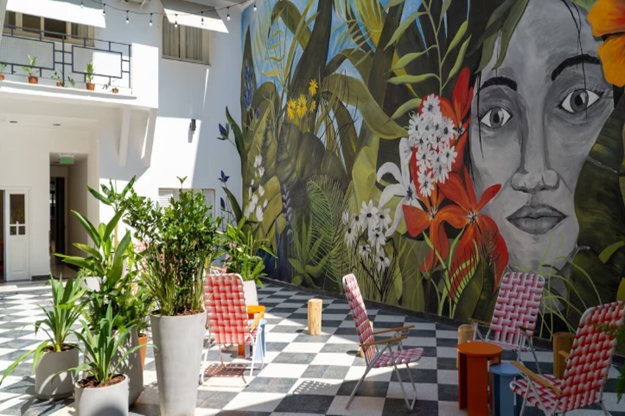 Un patio con suelo a cuadros, plantas en macetas y mobiliario exterior.