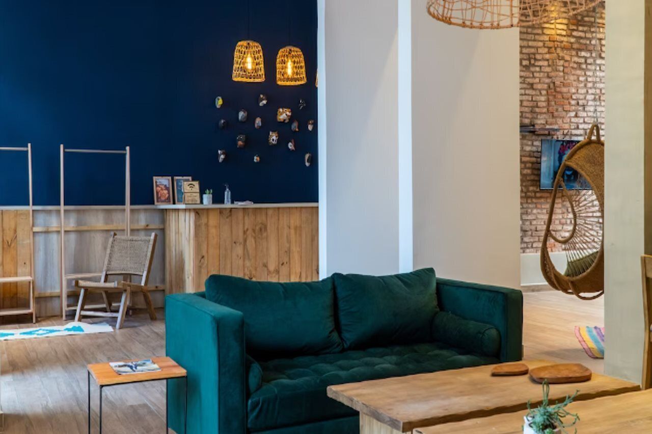 Una sala acogedora con un sofá azul verdoso, una mesa de centro de madera y sillas colgantes de mimbre.