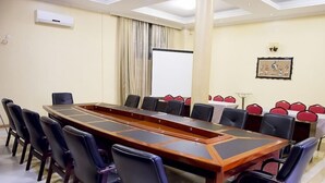 A conference room with a long table, black chairs, a whiteboard, and a projector screen. - Martha Hotel Bujumbura (Bujumbura)