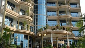 A multi-story hotel with a curved facade, balconies, and a central entrance with steps. - Martha Hotel Bujumbura (Bujumbura)