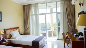 A hotel room with two beds, a desk, a chair, a phone, and a view of the outdoors through large windows. - Martha Hotel Bujumbura (Bujumbura)