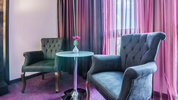A room with two armchairs, a small round table, and a vase with a flower. - Best Boutique Hotel (Stara Zagora)