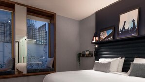 A modern bedroom with a large bed, a window with a view of buildings, and a dark headboard. - A-stay Antwerp (Antwerp)