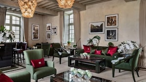 A spacious living room with green upholstered furniture, a glass coffee table, and a chandelier. - Chateau Lafaurie-peyraguey by Lalique (Bommes)