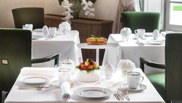 A dining area with tables set for four, white tablecloths, and green chairs. - Chateau Lafaurie-peyraguey by Lalique (Bommes)