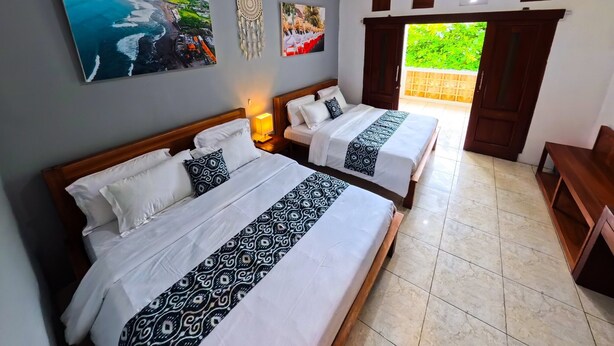 A hotel room with two beds, a large window, and artwork on the walls. - Ketapang Guest House Canggu by Zuzu (Canggu)