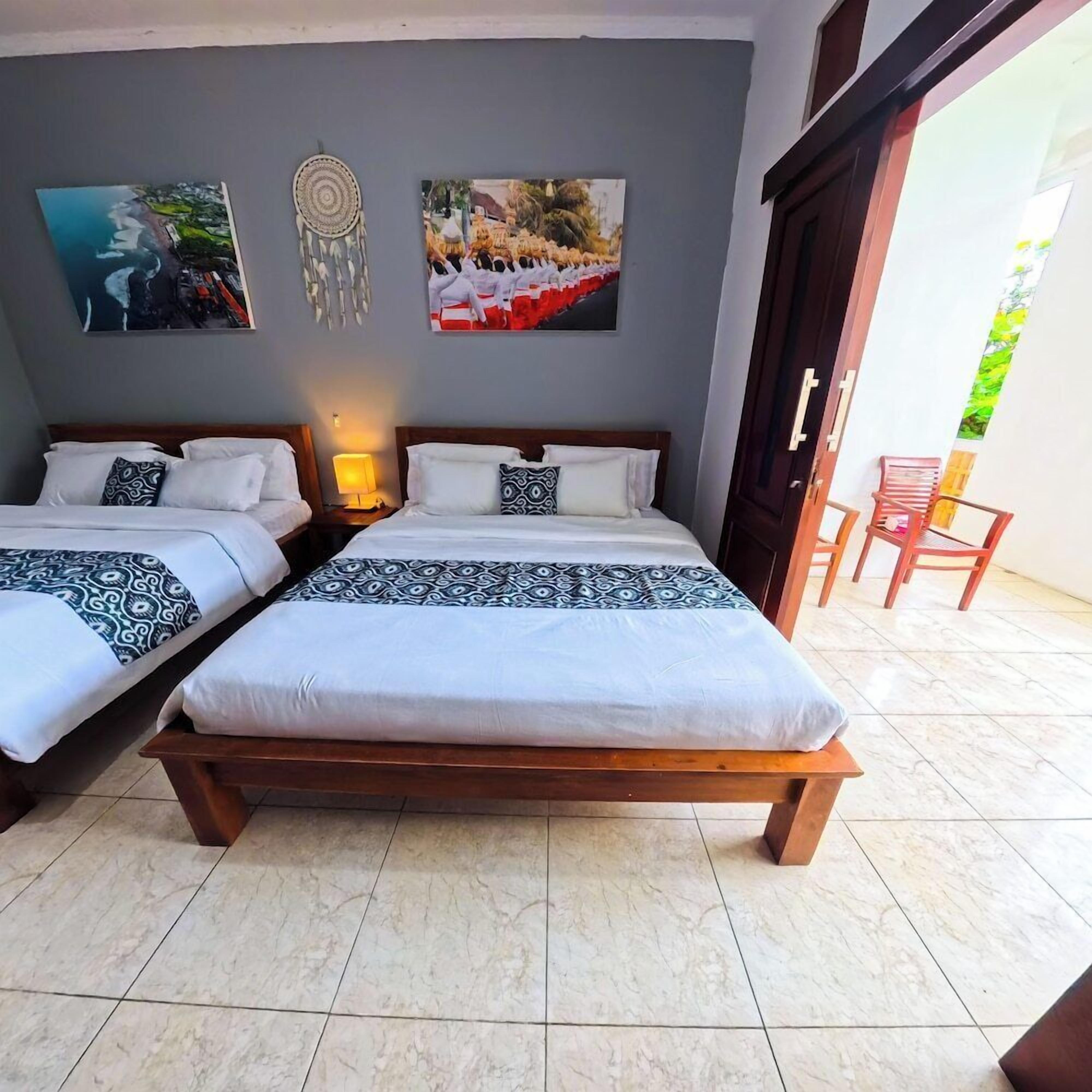 A double room with two beds, a nightstand with a lamp, and a view of the outside.