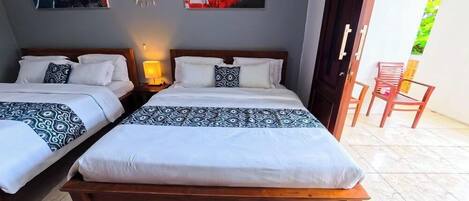 A double room with two beds, a nightstand with a lamp, and a view of the outside.