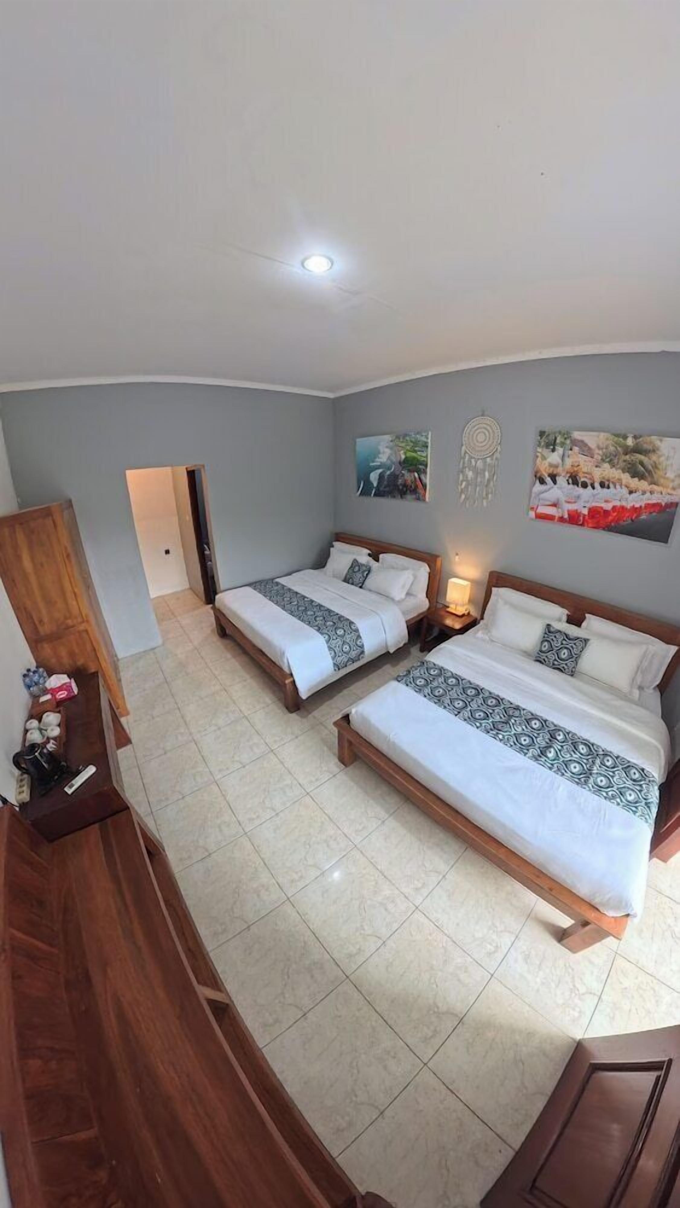 Een kamer met twee bedden, een houten garderobe, een bureau en een deur naar een andere kamer.