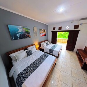 A hotel room with two beds, a large painting of a coastal scene, a dreamcatcher, and a view of greenery through a door. - Ketapang Guest House Canggu by Zuzu (Canggu)