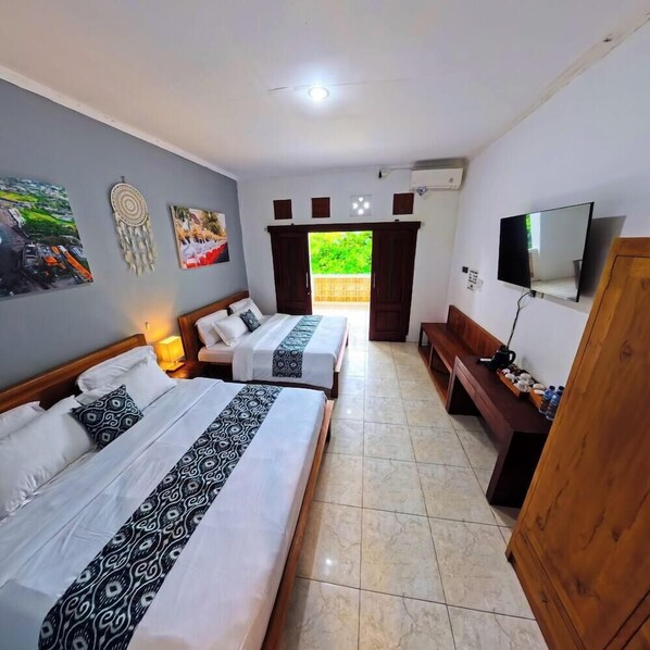 A hotel room with two beds, a TV, a bench, and a door. - Ketapang Guest House Canggu by Zuzu (Canggu)