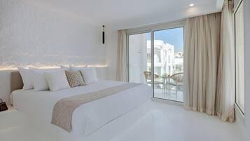 A modern bedroom with a large bed, a sliding glass door to a balcony, and a view of buildings.