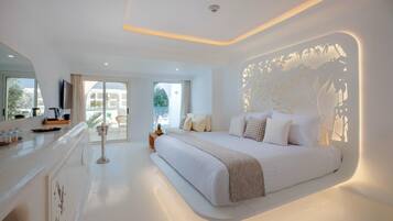 A modern hotel room with a large bed, a balcony with a view, and a kitchen area.