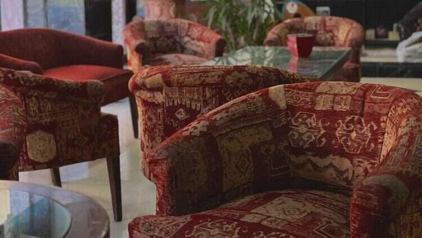 A library with patterned armchairs, a glass table, and bookshelves. - The Amman Pasha Hotel (Amman)