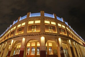 A traditional building with multiple arches and a central column, illuminated at night. - Sovereign Hotel (Doha)
