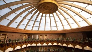 Ein großzügiger Innenhof mit einer gewölbten Glasdecke, mehreren Türen und Pflanzreihen.