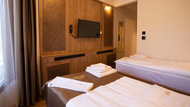 Ein Hotelzimmer mit zwei Betten, einem an einer Holzplatte befestigten Fernseher und einem Spiegel an der Wand.