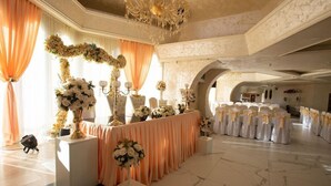 Ein prächtiger Saal mit einem langen Tisch, geschmückt mit floralen Arrangements und weißen Stühlen mit gelben Bändern.