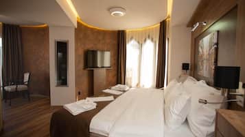 A hotel room with a large bed, a television, a desk with a lamp, and a painting on the wall.
