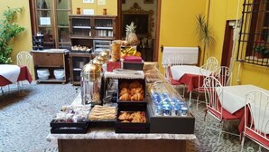 Een ontbijtbuffet met diverse gebakjes, fruit en drankjes.